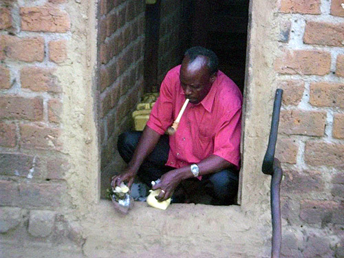 A 'traditional healer' performs a ceremony in the doorway of the house of an accused witch. The walking stick outside the door is the source of his power. 
