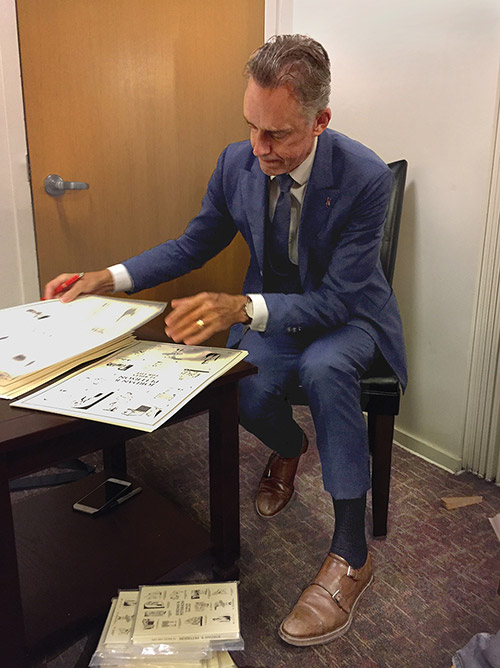 Jordan Peterson autographs copies of his 12 Rules for Life poster in the greenroom before his lecture.