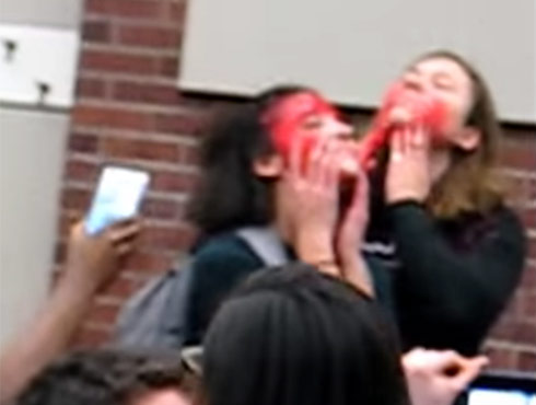 Students at Rutgers University protest a talk by Milo Yiannopoulos by smearing red on their faces and shouting 'hate' when he challenged them to hear other points of view.